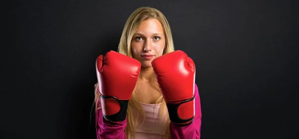 Pretty sport woman with boxing gloves on textured black background