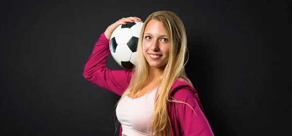 美丽的运动妇女拿着足球在纹理的黑色背景 — 图库照片