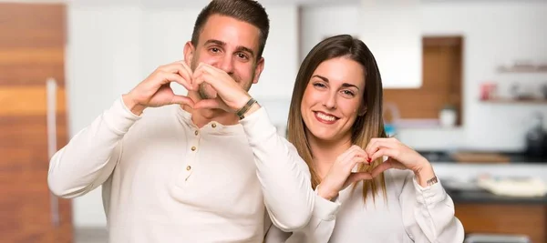 バレンタイン家で手でハートの記号を作る日のカップル — ストック写真