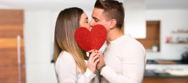 İki kalp simgesi tutan ve bir evde öpüşme valentines gün içinde