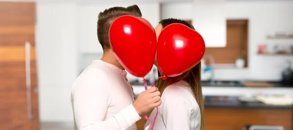 Couple in valentine day with balloons with heart shape in a house
