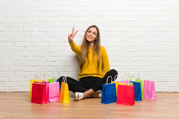 Fiatal Lány Sok Bevásárló Táskák Mosolyogva Bemutatja Győzelem Jele — Stock Fotó