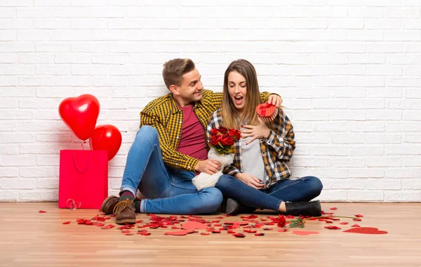 一对夫妇在情人节在室内鲜花和礼物 — 图库照片