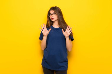 Sarı duvar yapma dur hareketi her iki el ile üzerinden gözlüklü genç kadın