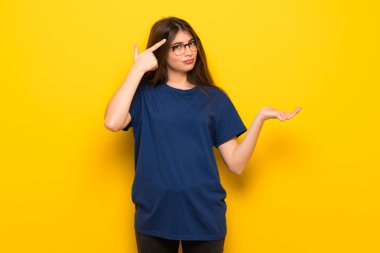 Parmak kafasına koyarak delilik jest yaparak sarı duvarın üzerinden gözlüklü genç kadın