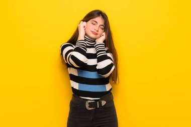 Sarı duvar eller kulaklar kaplama genç kadın. Hayal kırıklığı ifade