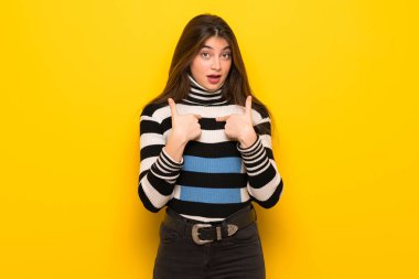 Sürpriz yüz ifadesi ile sarı duvarın üzerinden genç kadın