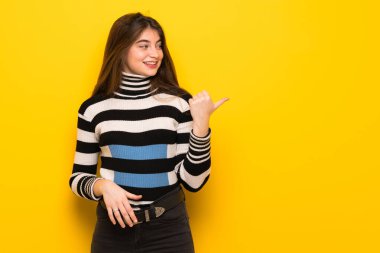 Ürün sunmak için sarı duvar tarafına işaret eden genç kadın