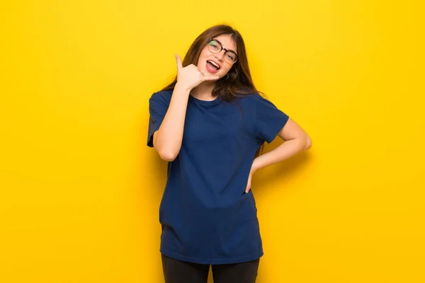 Mujer Joven Con Gafas Sobre Pared Amarilla Haciendo Gesto Teléfono —  Fotos de Stock