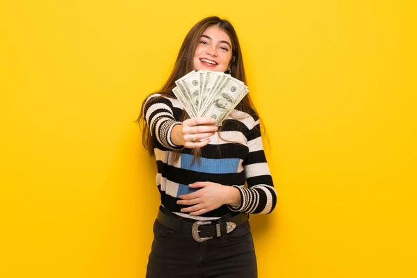 Joven Mujer Sobre Pared Amarilla Tomando Montón Dinero —  Fotos de Stock