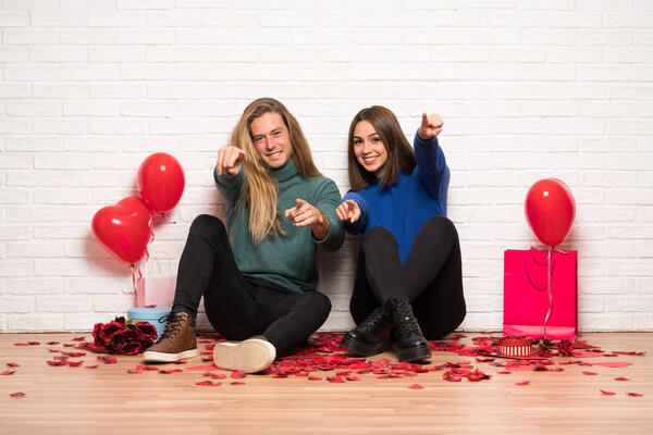 Couple in valentine day points finger at you with a confident expression