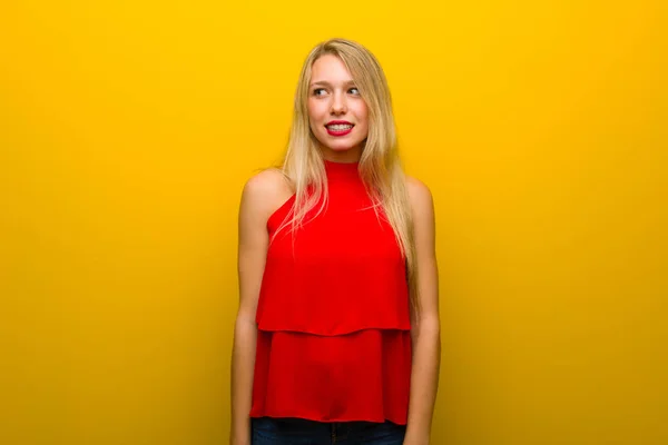 Biraz Gergin Korkmuş Diş Basarak Sarı Duvarın Üzerinden Kırmızı Elbise — Stok fotoğraf