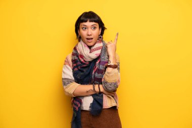Genç hippi kadın parmağı yukarıyı bir fikir düşünce sarı duvarın üzerinden