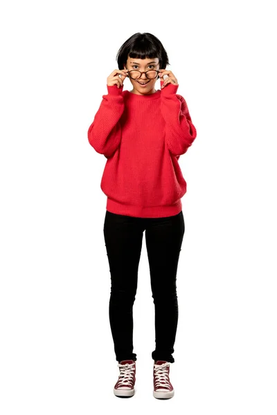 メガネと分離の白い背景にびっくりの赤いセーターと短い髪の女の子のフルレングス ショット — ストック写真