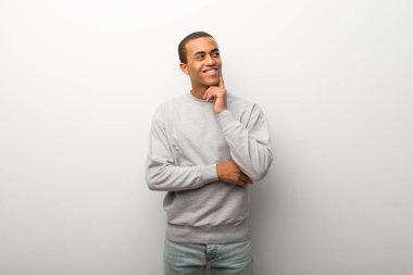 Afrika kökenli Amerikalı adam beyaz duvar arka planda bir fikir ararken süre düşünme