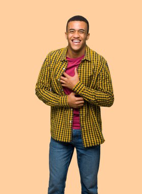 Çok izole arka plan üzerinde göğsünde el koyarken gülümseyen genç afro Amerikalı adam