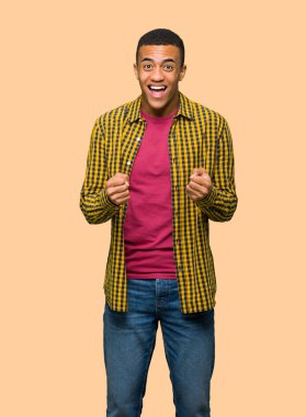 Genç afro Amerikalı adam kazanan pozisyon izole arka plan üzerinde bir zaferini kutluyor