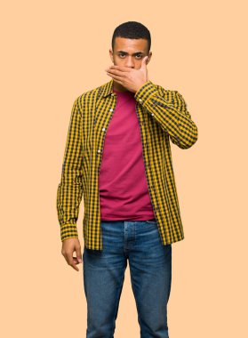 Genç afro Amerikalı adam ağız izole arka plan üzerinde uygunsuz bir şey söylediğin için elleriyle kapsayan