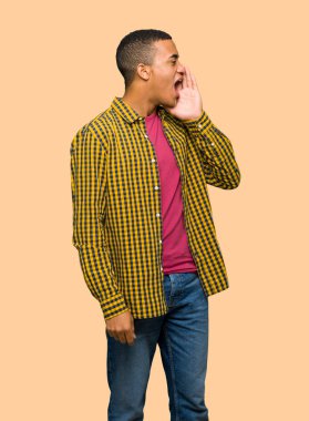 Genç afro Amerikalı adam lateral izole arka plan üzerine açık geniş ağızlı bağırarak