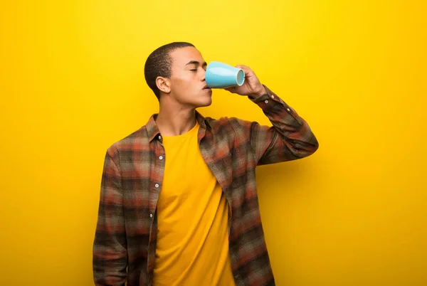 Junger Afrikanisch Amerikanischer Mann Auf Leuchtend Gelbem Hintergrund Trinkt Heißen — Stockfoto