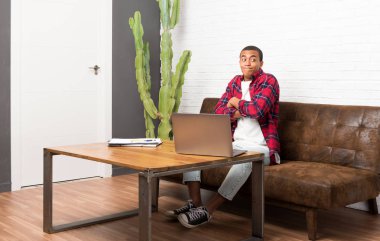 Omuz kaldırma sırasında jest ile laptop oturma odası yapımında Afrikalı-Amerikalı adam şüphe