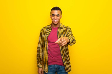 Genç afro Amerikalı adam sarı arka plan üzerinde parmak seni kendinden emin bir ifadesiyle işaret