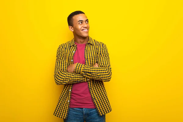 Joven Afroamericano Sobre Fondo Amarillo Mirando Hacia Arriba Mientras Sonríe —  Fotos de Stock