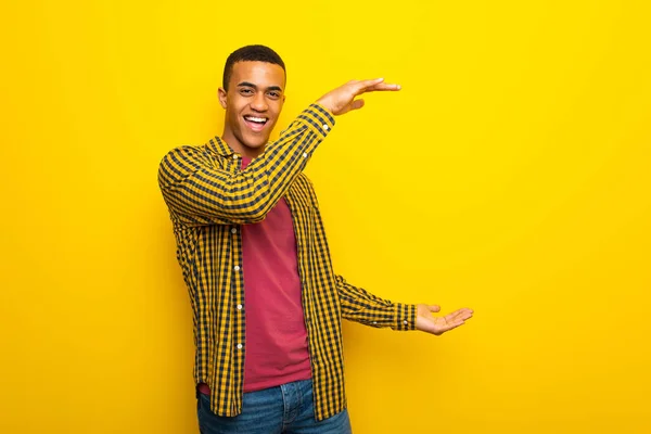 年轻的非洲裔美国人在黄色背景持有复制空间插入广告 — 图库照片
