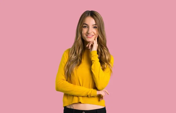 年轻的女孩与黄色毛衣微笑 并期待着前面与自信的脸在孤立的粉红色背景 — 图库照片
