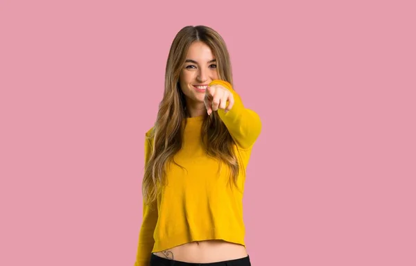 分離ピンク背景に自信を持って式に黄色いセーターを着てポイントの指を持つ少女 — ストック写真