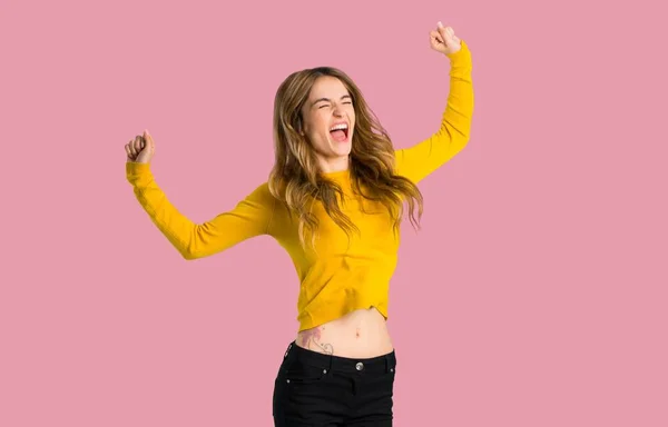 黄色いセーターを着て幸せと分離ピンク背景にジャンプを持つ少女 — ストック写真