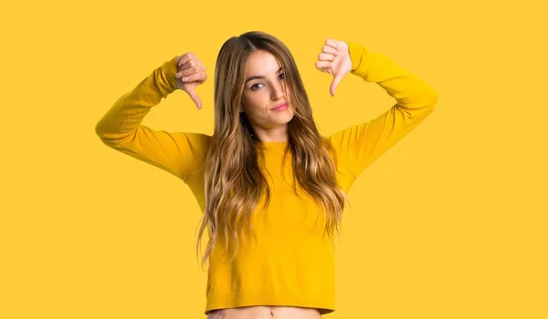 노란색 배경에 양손으로 엄지를 보여주는 스웨터와 — 스톡 사진