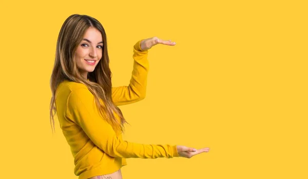 Muchacha Joven Con Suéter Amarillo Sosteniendo Copyspace Para Insertar Anuncio —  Fotos de Stock