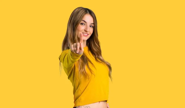 Jovem Com Suéter Amarelo Mostrando Levantando Dedo Fundo Amarelo Isolado — Fotografia de Stock