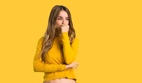 分離された黄色の背景に疑問を持つ黄色のセーターを持つ少女 — ストック写真