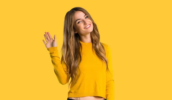 黄色いセーターを着て敬礼で分離された黄色の背景に幸せな式手を持つ少女 — ストック写真