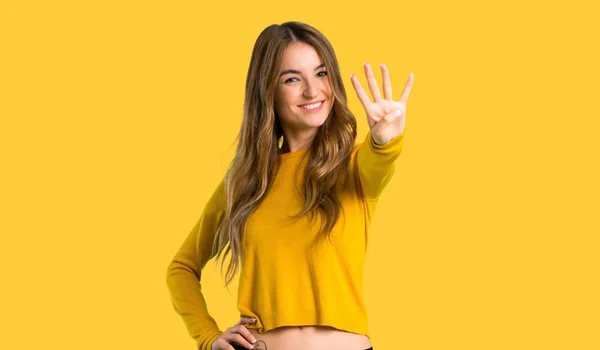 sarı kazaklı mutlu ve sayım dört parmaklı izole sarı zemin üzerine genç kız