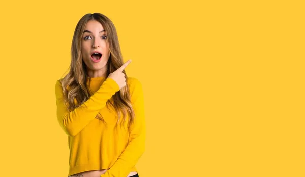 Chica Joven Con Suéter Amarillo Sorprendido Apuntando Lado Sobre Fondo —  Fotos de Stock