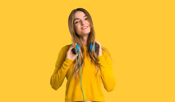 헤드폰을 노란색 배경에 스웨터와 — 스톡 사진