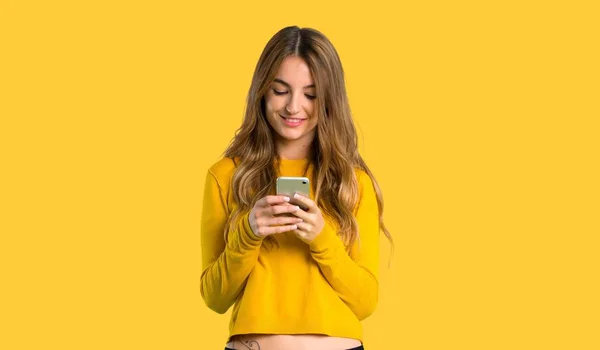 Młoda Dziewczyna Żółty Sweterek Wysłanie Wiadomości Telefonu Białym Tle Żółty — Zdjęcie stockowe