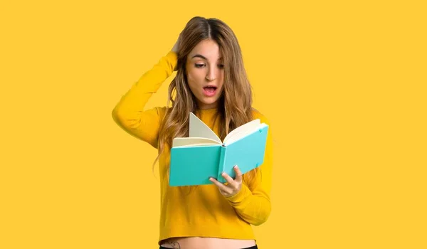 Fiatal Lány Meglepett Miközben Olvasott Elszigetelt Sárga Alapon Sárga Pulóver — Stock Fotó