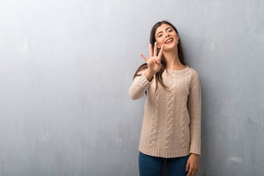 Kazak üzerine bir duvar mutlu ve sayım dört parmak ile genç kızla