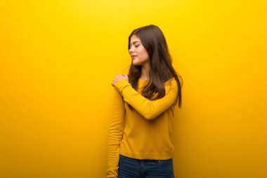 Canlı sarı arka plana sahip yapılmış bir çaba için omuz ağrısı muzdarip genç kız