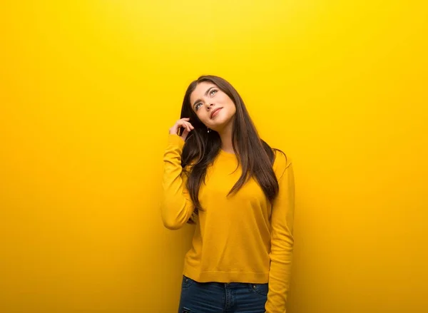 Menina Adolescente Fundo Amarelo Vibrante Pensando Uma Ideia Enquanto Coça — Fotografia de Stock