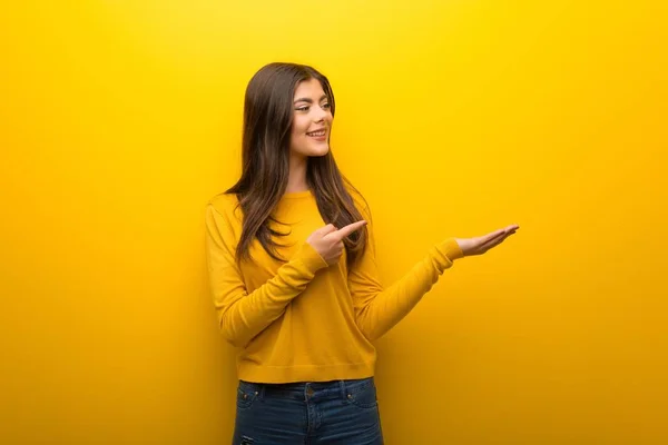 Menina Adolescente Fundo Amarelo Vibrante Segurando Copyspace Imaginário Palma Mão — Fotografia de Stock