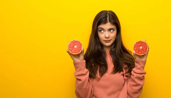 Nastolatek Dziewczyna Różowy Bluza Żółtym Tle Pomarańczami — Zdjęcie stockowe