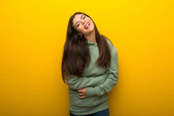 Chica Adolescente Con Sudadera Verde Sobre Fondo Amarillo Manteniendo Los —  Fotos de Stock