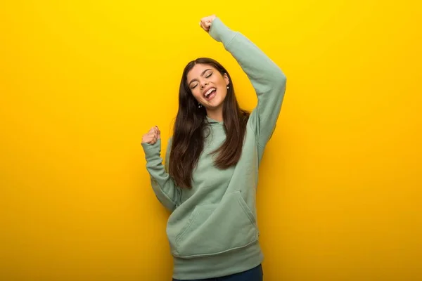 Chica Adolescente Con Sudadera Verde Sobre Fondo Amarillo Celebrando Una — Foto de Stock