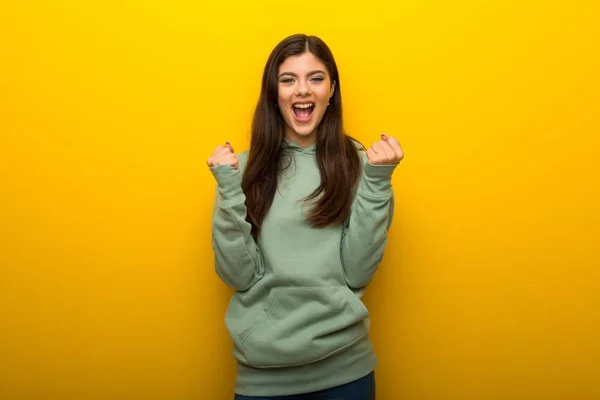 Tiener Meisje Met Groene Sweater Gele Achtergrond Vieren Een Overwinning — Stockfoto