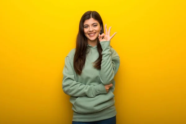 Teenager Mädchen Mit Grünem Sweatshirt Auf Gelbem Hintergrund Zeigt Ein — Stockfoto